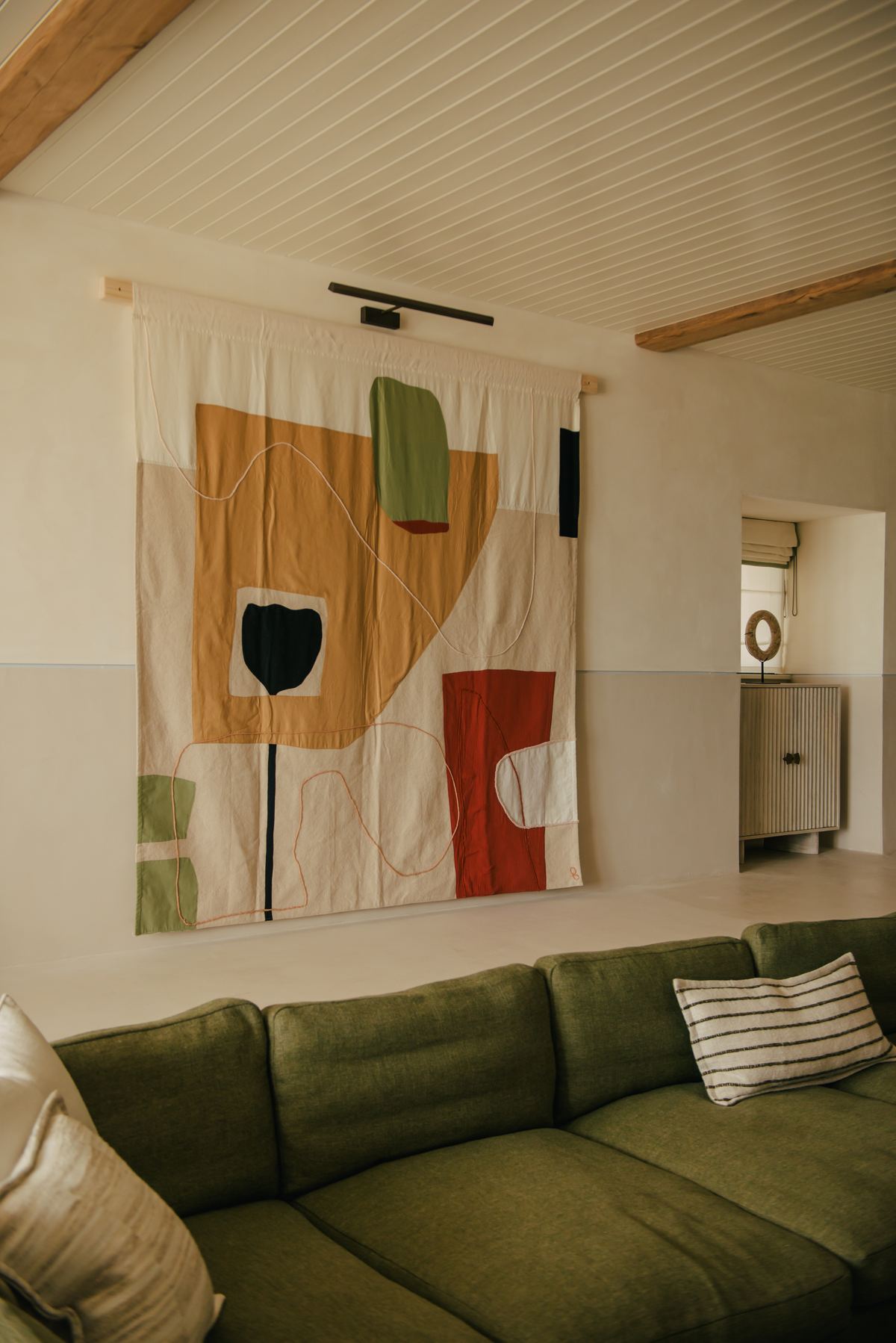 Green sofa beneath a hanging artwork