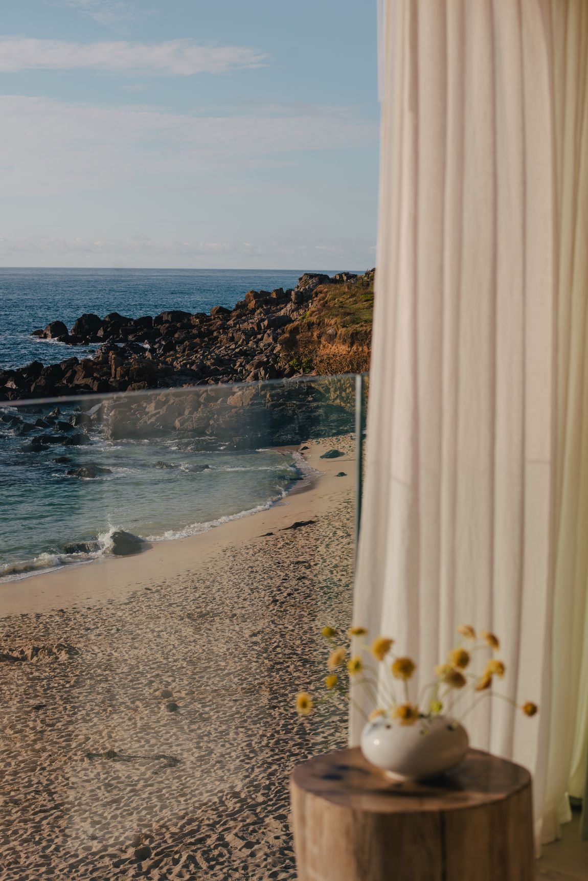 Linen curtain drawn back to the sand and sea