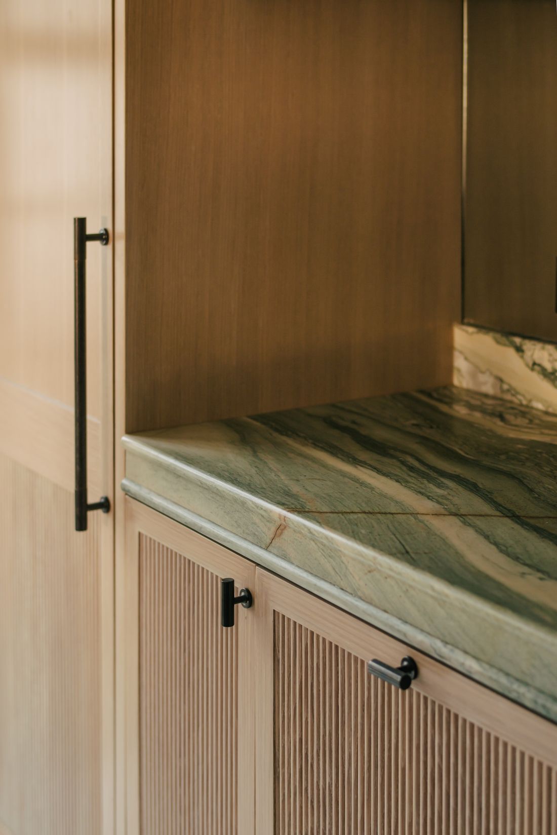 Green marble worktop against fluted oak
